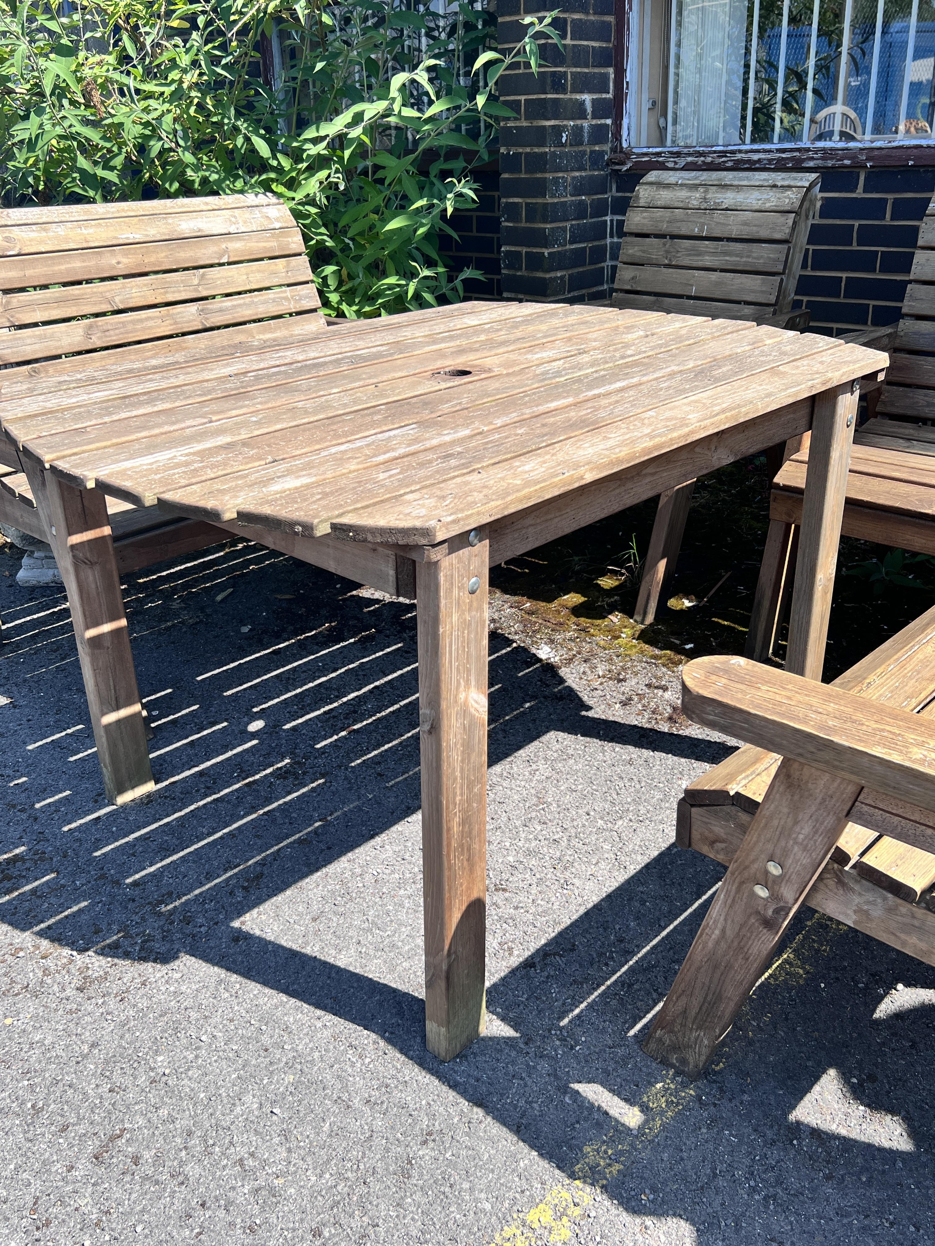 A rectangular slatted teak garden table, length 130cm, width 96cm, height 79cm, together with a pair of armchairs and a pair of benches